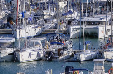 İtalya, Sicilya, Akdeniz, Marina di Ragusa (Ragusa Eyaleti); 7 Ekim 2021, limandaki bir yelkenli ve lüks yatlarda yaşayan insanlar - EDITORIAL