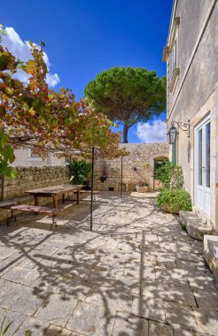 İtalya, Sicilya, Modica (Ragusa Eyaleti), kırsal kesim, masa ve eski bir taş evin koltukları ile yan avlu 