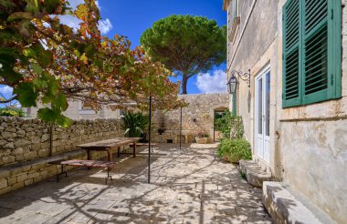 İtalya, Sicilya, Modica (Ragusa Eyaleti), kırsal kesim, masa ve eski bir taş evin koltukları ile yan avlu 