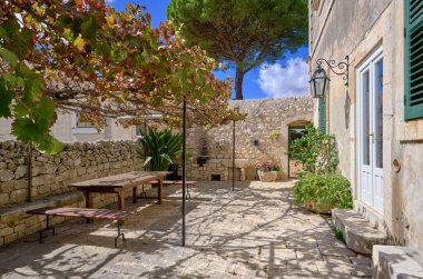 İtalya, Sicilya, Modica (Ragusa Eyaleti), kırsal kesim, masa ve eski bir taş evin koltukları ile yan avlu 