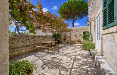 İtalya, Sicilya, Modica (Ragusa Eyaleti), kırsal kesim, masa ve eski bir taş evin koltukları ile yan avlu 