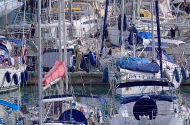 İtalya, Sicilya, Akdeniz, Marina di Ragusa (Ragusa Eyaleti); 1 Kasım 2021, limanda elektrikli scooter ve lüks yatlarda bir adam - EDITORIAL