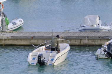 İtalya, Sicilya, Akdeniz, Marina di Ragusa (Ragusa Eyaleti); 1 Kasım 2021, limandaki bir motorlu teknede adam - EDITORIAL