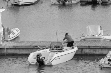 İtalya, Sicilya, Akdeniz, Marina di Ragusa (Ragusa Eyaleti); 1 Kasım 2021, limandaki bir motorlu teknede adam - EDITORIAL