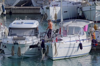 İtalya, Sicilya, Akdeniz, Marina di Ragusa (Ragusa Eyaleti); 13 Kasım 2021, limanda bisiklet ve lüks yatları olan adam - EDITORIAL