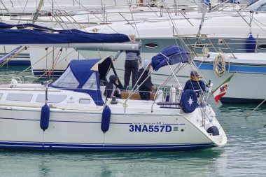 İtalya, Sicilya, Akdeniz, Marina di Ragusa (Ragusa Eyaleti); 21 Kasım 2021, limandaki bir yelkenli ve lüks yatlarda yaşayan insanlar - EDITORIAL