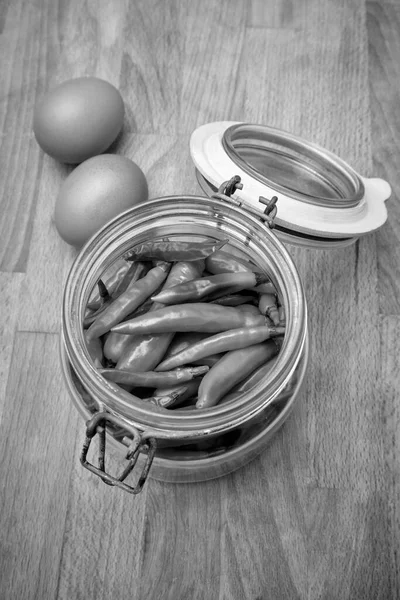 イタリア シチリア島 ガラス容器に新鮮なシチリア赤唐辛子とキッチン木製のテーブルの上の卵 — ストック写真