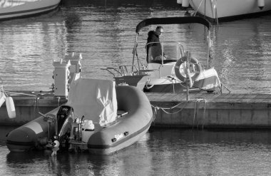 Italy, Sicily, Mediterranean Sea, Marina di Ragusa (Ragusa Province); 2 January 2022, man on a motor boat and luxury yachts in the port - EDITORIAL