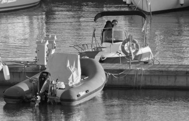 Italy, Sicily, Mediterranean Sea, Marina di Ragusa (Ragusa Province); 2 January 2022, man on a motor boat and luxury yachts in the port - EDITORIAL