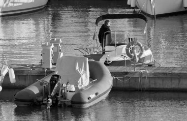 Italy, Sicily, Mediterranean Sea, Marina di Ragusa (Ragusa Province); 2 January 2022, man on a motor boat and luxury yachts in the port - EDITORIAL