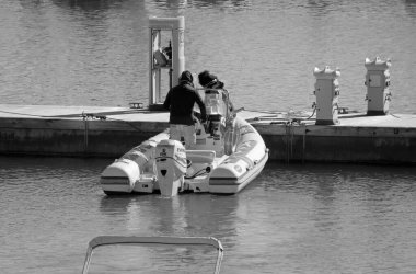 İtalya, Sicilya, Akdeniz, Marina di Ragusa (Ragusa ili); 15 Ocak 2022, limanda bir kauçuk teknede çift - EDITORIAL