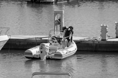 İtalya, Sicilya, Akdeniz, Marina di Ragusa (Ragusa ili); 15 Ocak 2022, limanda bir kauçuk teknede çift - EDITORIAL