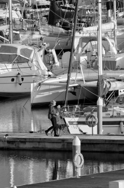 İtalya, Sicilya, Akdeniz, Marina di Ragusa (Ragusa Eyaleti); 18 Ocak 2022, limanda köpeği ve lüks yatları olan kadın - EDITORIAL