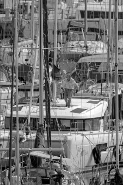 İtalya, Sicilya, Akdeniz, Marina di Ragusa (Ragusa Eyaleti); 29 Mart 2022, limandaki bir yelkenli teknesi ve lüks yatlarda adam - EDITORIAL