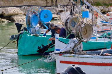 İtalya, Sicilya, Akdeniz, Scoglitti (Ragusa Eyaleti); 29 Mart 2022, limanda ahşap bir balıkçı teknesinde çalışan balıkçılar