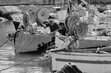İtalya, Sicilya, Akdeniz, Scoglitti (Ragusa Eyaleti); 29 Mart 2022, limanda ahşap bir balıkçı teknesinde çalışan balıkçılar