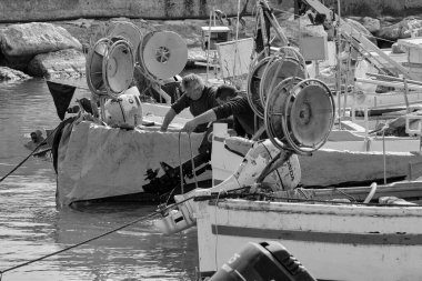 İtalya, Sicilya, Akdeniz, Scoglitti (Ragusa Eyaleti); 29 Mart 2022, limanda ahşap bir balıkçı teknesinde çalışan balıkçılar