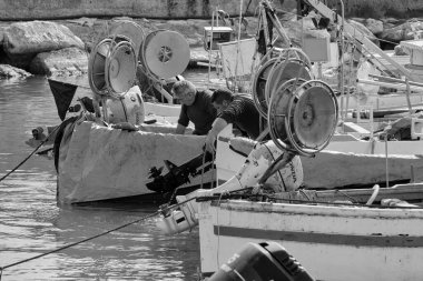 İtalya, Sicilya, Akdeniz, Scoglitti (Ragusa Eyaleti); 29 Mart 2022, limanda ahşap bir balıkçı teknesinde çalışan balıkçılar
