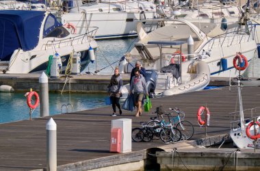 İtalya, Sicilya, Akdeniz, Marina di Ragusa (Ragusa Eyaleti); 3 Nisan 2022, limanda insanlar, bisikletler ve lüks yatlar - EDITORIAL