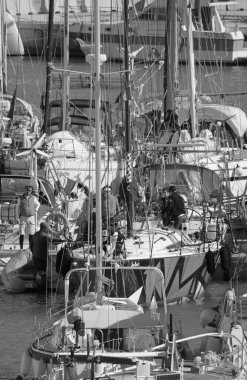 İtalya, Sicilya, Akdeniz, Marina di Ragusa (Ragusa Eyaleti); 9 Nisan 2022, limandaki bir yelkenli teknesi ve lüks yatlarda erkekler - EDITORIAL