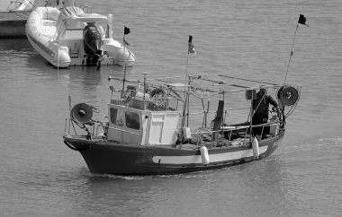 İtalya, Sicilya, Akdeniz, Marina di Ragusa (Ragusa Eyaleti); 12 Nisan 2022, limandaki ahşap balıkçı teknesinde balıkçı - EDITORIAL