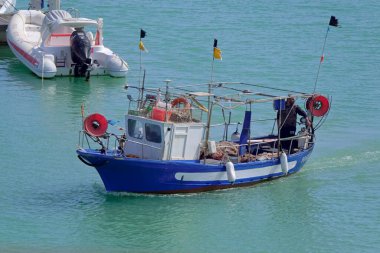 İtalya, Sicilya, Akdeniz, Marina di Ragusa (Ragusa Eyaleti); 12 Nisan 2022, limandaki ahşap balıkçı teknesinde balıkçı - EDITORIAL