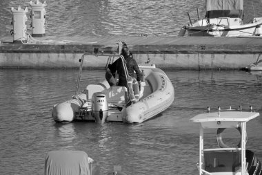 İtalya, Sicilya, Akdeniz, Marina di Ragusa (Ragusa Eyaleti); 19 Nisan 2022, limanda kauçuk bir tekne ve lüks yatlarda bir çift - EDITORIAL