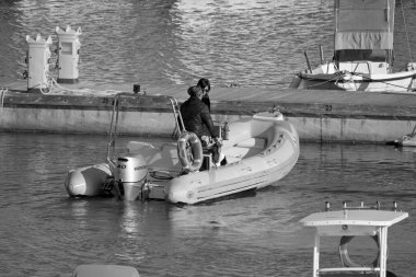 İtalya, Sicilya, Akdeniz, Marina di Ragusa (Ragusa Eyaleti); 19 Nisan 2022, limanda kauçuk bir tekne ve lüks yatlarda bir çift - EDITORIAL