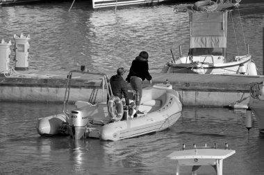 İtalya, Sicilya, Akdeniz, Marina di Ragusa (Ragusa Eyaleti); 19 Nisan 2022, limanda kauçuk bir tekne ve lüks yatlarda bir çift - EDITORIAL