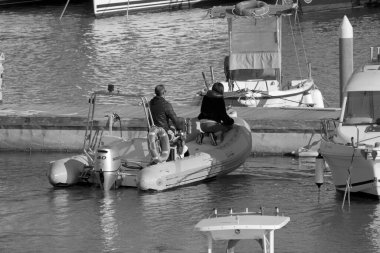 İtalya, Sicilya, Akdeniz, Marina di Ragusa (Ragusa Eyaleti); 19 Nisan 2022, limanda kauçuk bir tekne ve lüks yatlarda bir çift - EDITORIAL