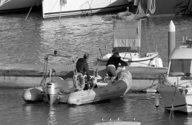 İtalya, Sicilya, Akdeniz, Marina di Ragusa (Ragusa Eyaleti); 19 Nisan 2022, limanda kauçuk bir tekne ve lüks yatlarda bir çift - EDITORIAL