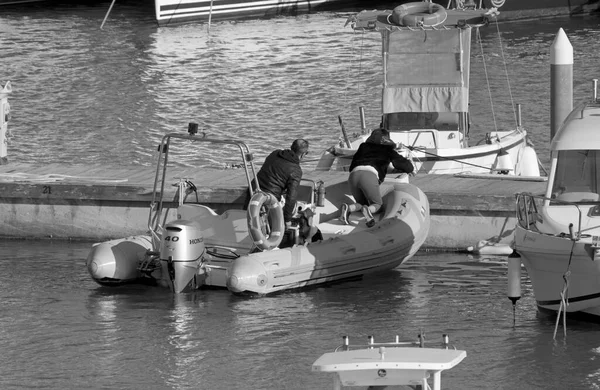 İtalya, Sicilya, Akdeniz, Marina di Ragusa (Ragusa Eyaleti); 19 Nisan 2022, limanda kauçuk bir tekne ve lüks yatlarda bir çift - EDITORIAL