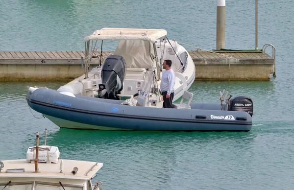 İtalya, Sicilya, Akdeniz, Marina di Ragusa (Ragusa Eyaleti); 24 Nisan 2022, limandaki kauçuk bir teknede adam - EDITORIAL