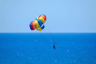 İtalya, Sicilya, Akdeniz, Marina di Ragusa (Ragusa Eyaleti); insanlar bir motorlu tekne tarafından çekilen bir paraşütle denizin üzerinde uçuyorlar.