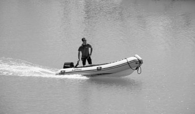 İtalya, Sicilya, Akdeniz, Marina di Ragusa (Ragusa Eyaleti); 15 Temmuz 2022, limandaki kauçuk bir teknede adam - EDITORIAL