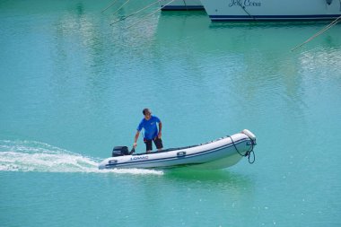 İtalya, Sicilya, Akdeniz, Marina di Ragusa (Ragusa Eyaleti); 15 Temmuz 2022, limandaki kauçuk bir teknede adam - EDITORIAL