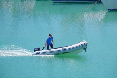 İtalya, Sicilya, Akdeniz, Marina di Ragusa (Ragusa Eyaleti); 15 Temmuz 2022, limandaki kauçuk bir teknede adam - EDITORIAL