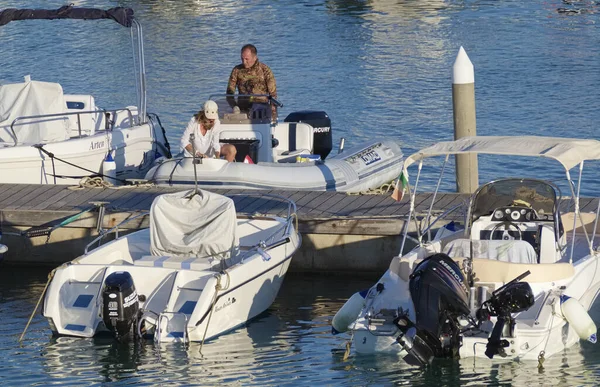 İtalya, Sicilya, Akdeniz, Marina di Ragusa (Ragusa Eyaleti); 15 Temmuz 2022, limanda kauçuk bir tekne ve lüks yatlarda bir çift - EDITORIAL