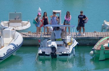 İtalya, Sicilya, Akdeniz, Marina di Ragusa (Ragusa ili); 17 Temmuz 2022, limanda insanlar ve motorlu tekneler - EDITORIAL