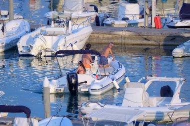 İtalya, Sicilya, Akdeniz, Marina di Ragusa (Ragusa Eyaleti); 19 Temmuz 2022, limandaki kauçuk tekne ve lüks yatlarda yaşayan insanlar - EDITORIAL