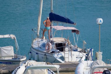 İtalya, Sicilya, Akdeniz, Marina di Ragusa (Ragusa Eyaleti); 20 Temmuz 2022, limandaki bir yelkenli teknesinde adam - EDITORIAL