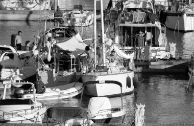 İtalya, Sicilya, Akdeniz, Marina di Ragusa (Ragusa Eyaleti); 16 Temmuz 2022, limandaki bir yelkenli ve lüks yatlarda erkekler