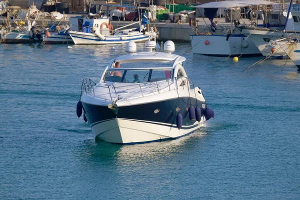 İtalya, Sicilya, Akdeniz, Marina di Ragusa (Ragusa ili); 30 Temmuz 2022, lüks bir yat ve limandaki yerel balıkçı tekneleri - EDITORIAL