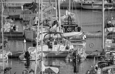 Italy, Sicily, Mediterranean Sea, Marina di Ragusa (Ragusa Province); 9 August 2022, couple on a sailing boat and luxury yachts in the port - EDITORIAL