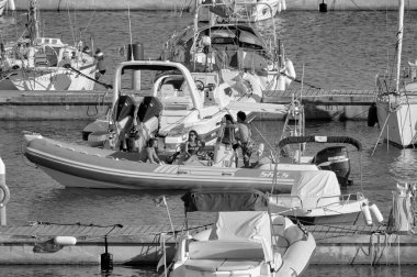 Italy, Sicily, Mediterranean Sea, Marina di Ragusa (Ragusa Province); 27 August 2022, people on a rubber boat and luxury yachts in the port - EDITORIAL