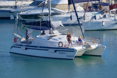 Italy, Sicily, Mediterranean Sea, Marina di Ragusa (Ragusa Province); 27 August 2022, people on a catamaran sailing boat and luxury yachts in the port - EDITORIAL