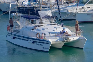Italy, Sicily, Mediterranean Sea, Marina di Ragusa (Ragusa Province); 27 August 2022, people on a catamaran sailing boat and luxury yachts in the port - EDITORIAL