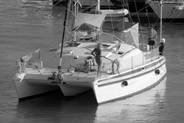 Italy, Sicily, Mediterranean Sea, Marina di Ragusa (Ragusa Province); 27 August 2022, people on a catamaran sailing boat and luxury yachts in the port - EDITORIAL