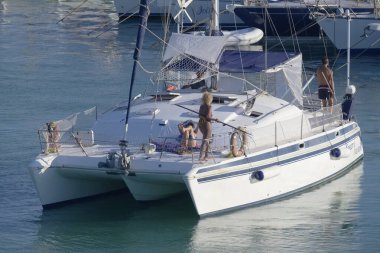 Italy, Sicily, Mediterranean Sea, Marina di Ragusa (Ragusa Province); 27 August 2022, people on a catamaran sailing boat and luxury yachts in the port - EDITORIAL