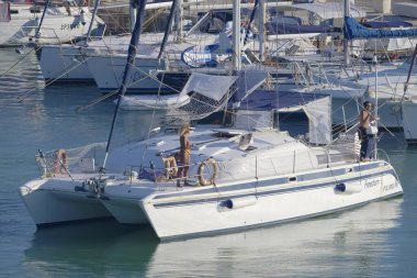 Italy, Sicily, Mediterranean Sea, Marina di Ragusa (Ragusa Province); 27 August 2022, people on a catamaran sailing boat and luxury yachts in the port - EDITORIAL